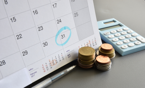 Calendar with the 31st circled in blue, pennies stacked and calculator.