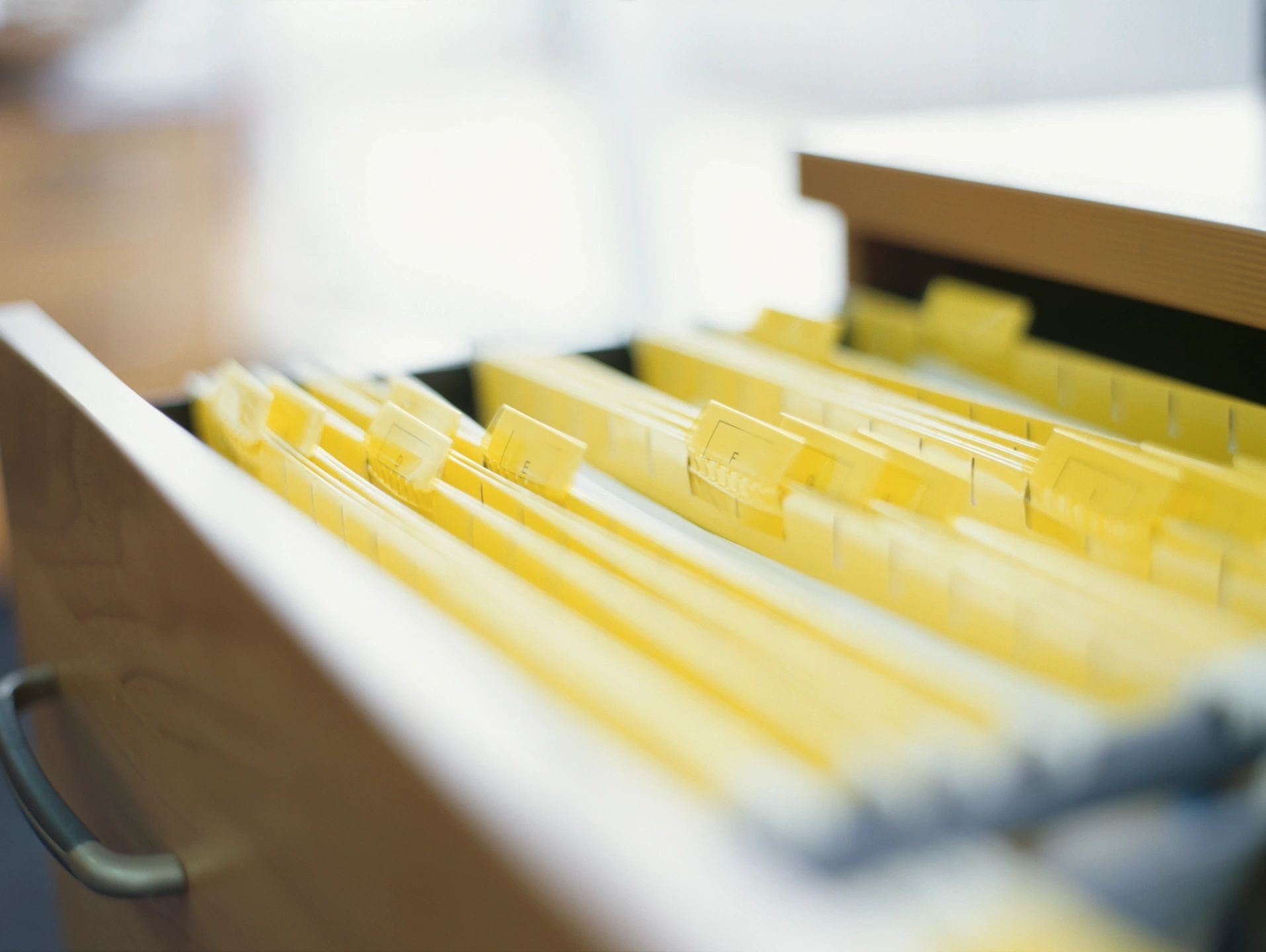 Yellow files inside a filing drawer.