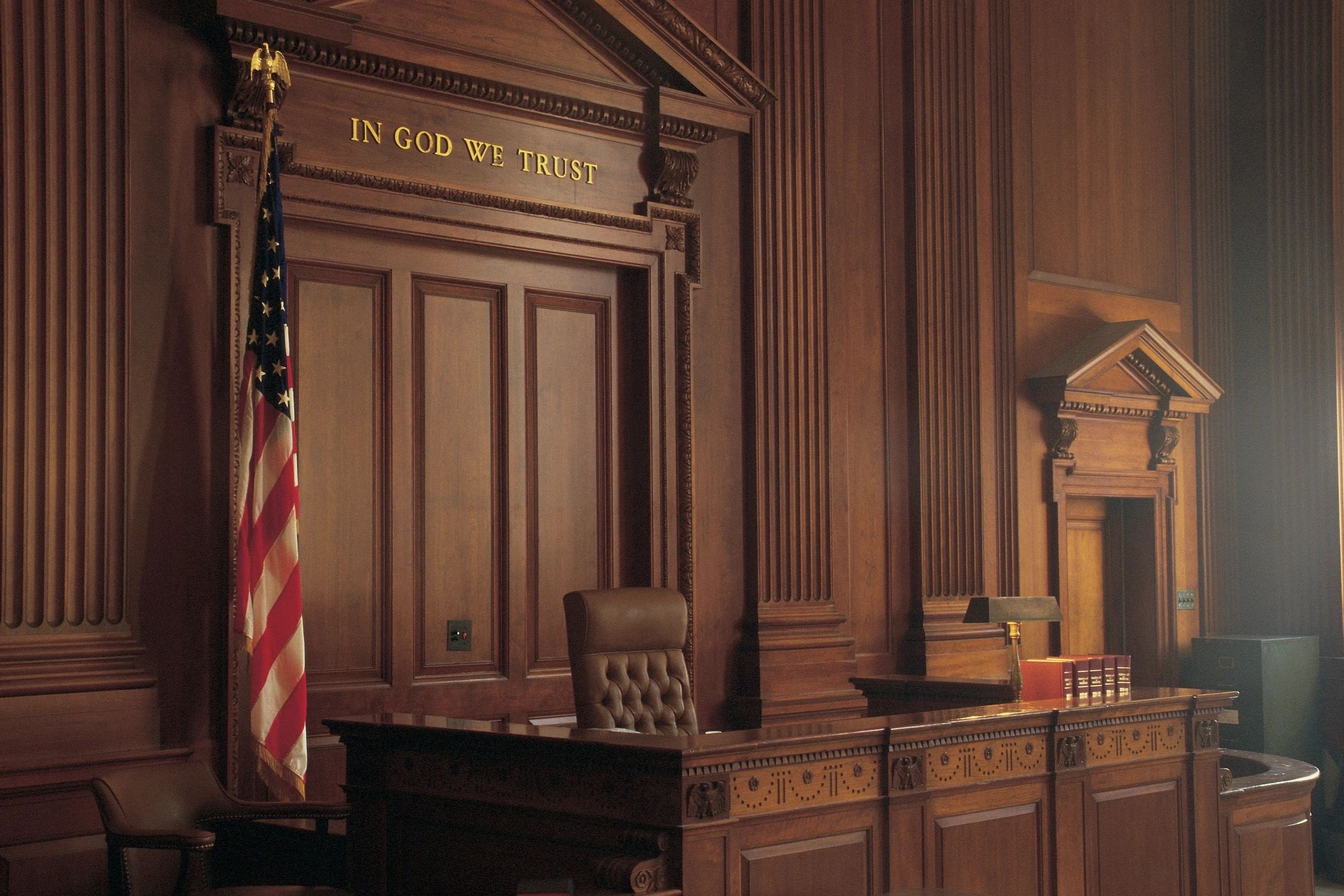 Judge stand in a courtroom with American flag.